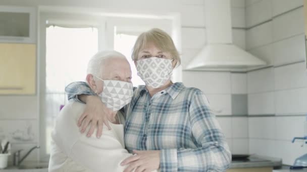 Una anciana abrazando a su hija en la cocina. Ambas mujeres con máscaras médicas para protegerse contra la infección viral. — Vídeo de stock