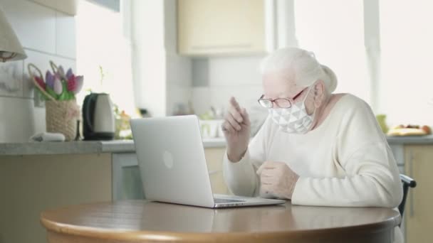 Een oude vrouw in masker voor bescherming tijdens de epidemie van Virale Infectie zet op glazen. — Stockvideo