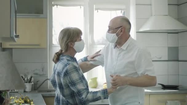 Mężczyzna i kobieta w maskach medycznych taniec w kuchni. — Wideo stockowe