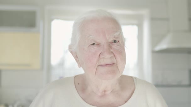 Egy idős nő portréja, amint a konyhában ül.. — Stock videók