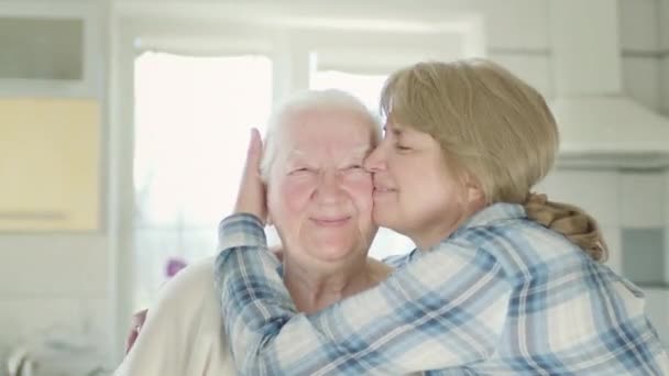Porträt zweier Frauen. Tochter umarmt ihre alte Mutter. Frauen in der Küche. — Stockvideo