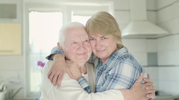 Portrait Of Two Women. Daughter Hugs Her Old Mom. Women In The Kitchen. — Stock Video