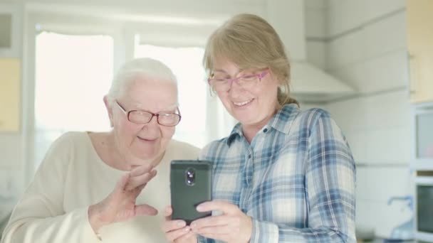 Retrato de dos mujeres. Hija mostrando algo a su vieja mamá en su celular. — Vídeos de Stock