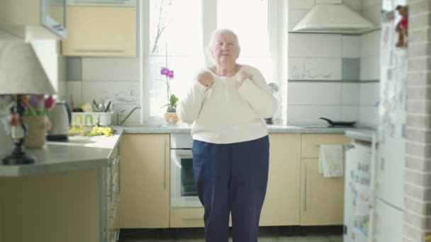 Старая бабушка занимается физическими упражнениями на кухне. — стоковое видео