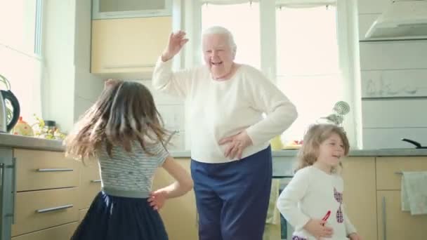 Старая бабушка танцует на кухне с двумя маленькими правнуками. — стоковое видео