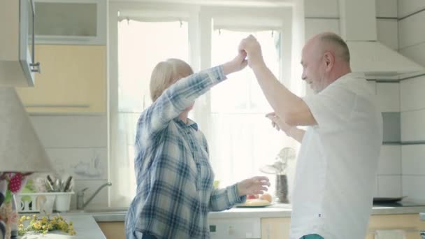 Зрелая пара танцует на кухне. — стоковое видео