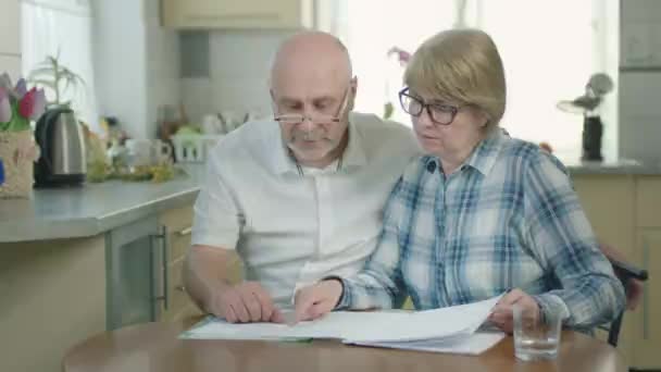 Volwassen paar man en vrouw in de keuken het lezen van een aantal documenten. — Stockvideo