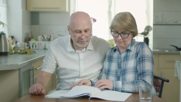 Reif pärchen mann und frau im die küche reading einige dokumente. — Stockvideo