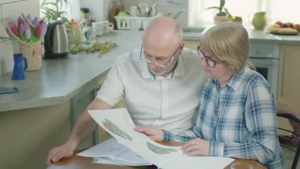 Volwassen paar man en vrouw in de keuken het lezen van een aantal documenten. — Stockvideo