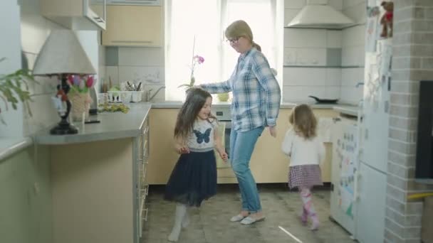 Бабушка танцует на кухне с двумя внучками. — стоковое видео