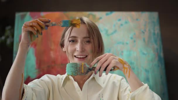 Genç kız boyaya batırılmış yüz fırçasının yanında duruyor.. — Stok video