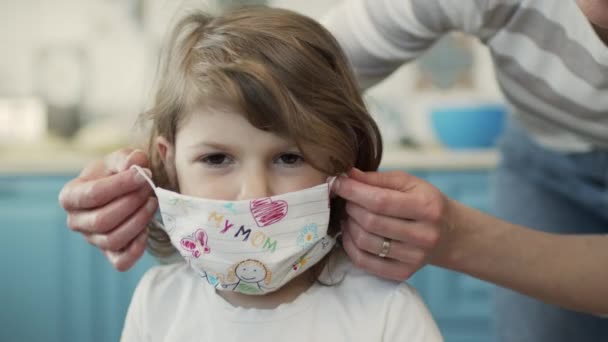 Mamá se pone la pequeña máscara médica para proteger contra la infección viral. — Vídeo de stock