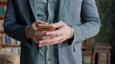 Ceketli Adam 'ın Elleri Akıllı Telefonu Tutuyor ve Kullanıyor.