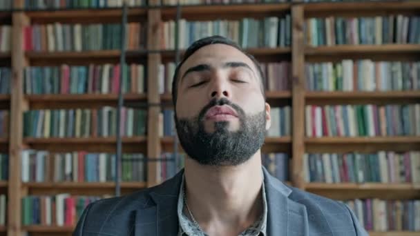 La cara de un tipo con barba en la biblioteca. — Vídeos de Stock