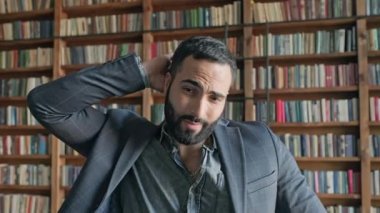 Kütüphanede ensesini tırmalayan şık bir genç adam..