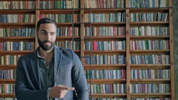 Stilvoller orientalischer junger Mann in der Bibliothek. — Stockvideo