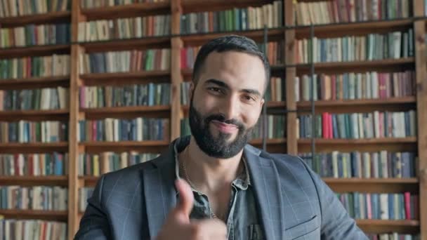 Chico con estilo en la biblioteca muestra con su mano que todo está bien. — Vídeos de Stock