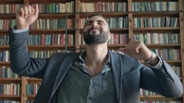 Genç adam kütüphanede kulaklıkla müzik dinliyor..