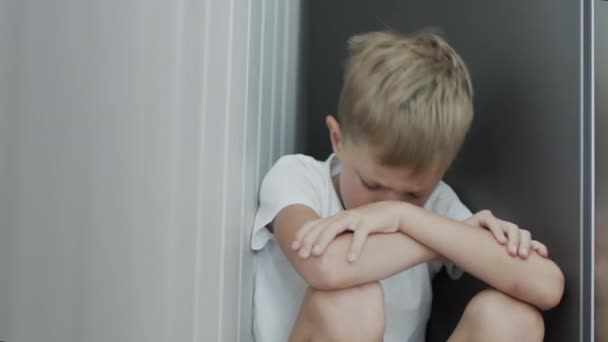 Üzgün küçük çocuk oturmuş dizlerine sarılıyor.. — Stok video