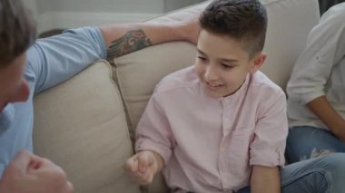 Apartmandaki koltukta oturan mutlu genç aile. Baba ve oğul gülüyor ve eğleniyorlar..