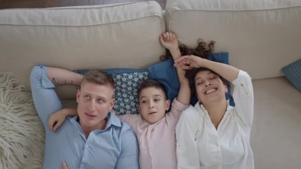 Νεαρή οικογένεια ξαπλωμένη στον καναπέ. Μαμά, μπαμπάς και γιος. Διασκεδάζουν.. — Αρχείο Βίντεο
