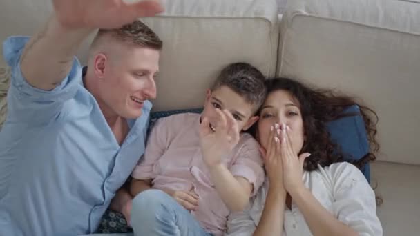 Giovane famiglia sdraiata sul divano. Mamma, papà e figlio. Si divertono. — Video Stock
