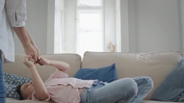 Çocuk elinde telefonla kanepede oturuyordu. Genç anne ona yaklaştı ve telefonu açmaya çalıştı.