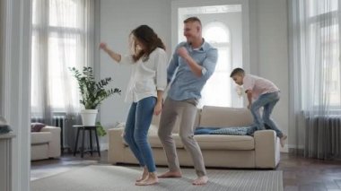 Boş zamanlarında genç bir aile babası ve annesi odada çıplak ayakla dans eder ve küçük oğlu kanepeye atlar..