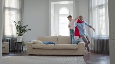 Baba ve Oğul apartmanda oyun oynuyorlar. Babam kırmızı pelerinli ve gözlüklü Süpermen 'i gösteriyor..