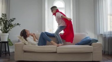 Anne ve Oğul odada. Kırmızı pelerinli ve gözlüklü çocuk Superman 'i oynuyor..