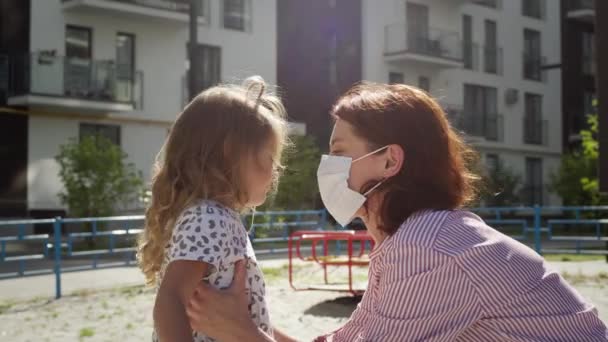 A fiatal anya megöleli a kislányát. Nő orvosi maszkot, hogy megvédje a fertőzések ellen. — Stock videók