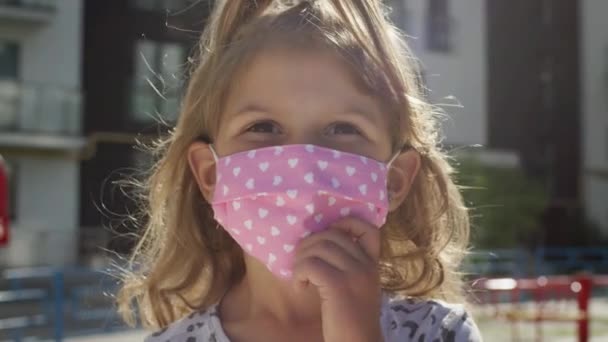 Портрет маленькой девочки в медицинской маске для защиты от эпидемии вирусной инфекции. — стоковое видео