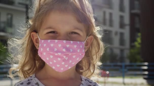 Viral enfeksiyon salgınından korunmak için tıbbi maskeli küçük bir kızın portresi. — Stok video