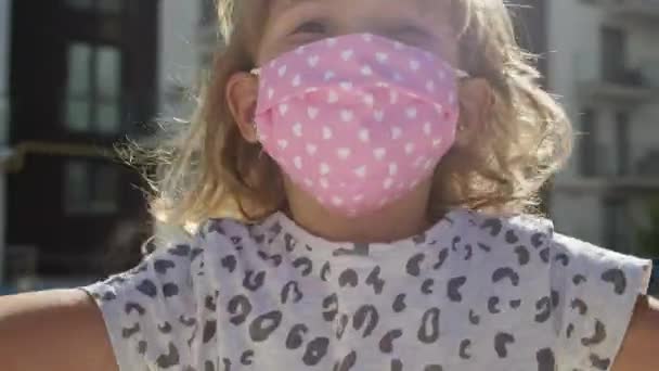 Portret van een klein meisje in een medisch masker om te beschermen tegen een epidemie van virale infectie. Meisje heeft plezier springen. — Stockvideo