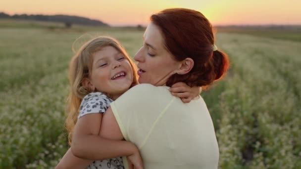 Giovane madre che tiene sua figlia tra le braccia. Sono nel bel mezzo del campo. Madre baci figlia. — Video Stock