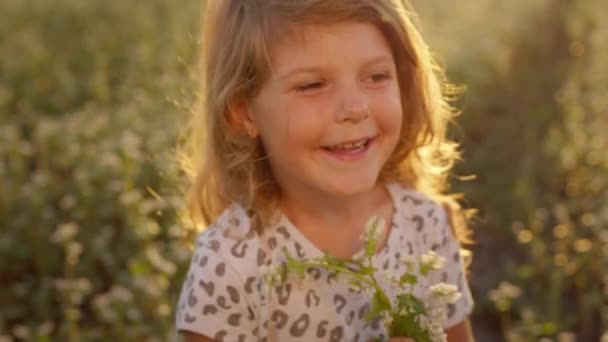Cara de menina. Ela está no campo. Menina brincando com flor. — Vídeo de Stock