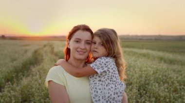 Genç Anne, kızını kollarında tutuyordu. Arazinin ortasındalar. İkisi de gülümsüyor..