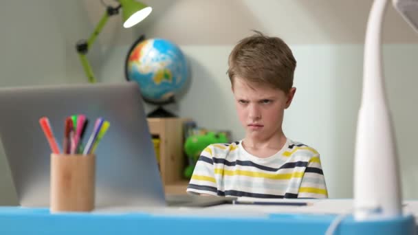 De jongen zit thuis op Laptop. Leuke zevenjarige jongen. Zijn Expressie is ontevreden. — Stockvideo