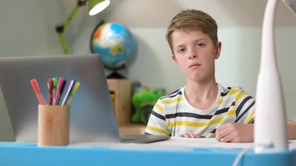 Ragazzo seduto al computer portatile a casa. carino sette anno vecchio ragazzo disegna. — Video Stock