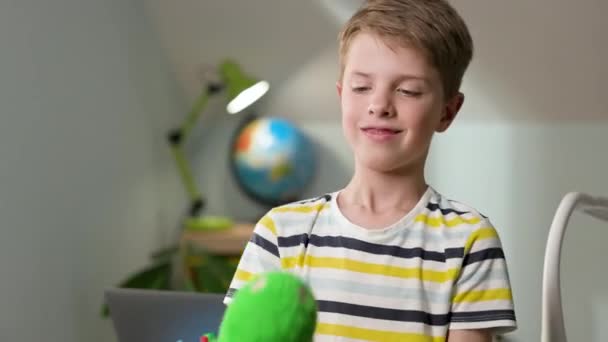 Menino de sete anos no berçário com brinquedo nas mãos. — Vídeo de Stock
