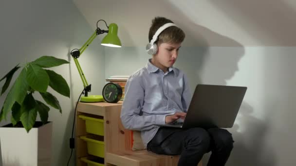 Garçon de dix assis dans la pépinière avec ordinateur portable sur son tour. — Video