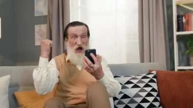 Koltukta oturan sakallı yaşlı adam. Gri sakalı ve bıyığı var ve yüzü kırışıklıklarla kaplı. Çok sevinir ve çeşitli jestler yaparak taşınır..