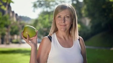 Büyük Yeşil Elmayı Tutan Mutlu Yaşlı Kadın. Uzun Gri Saçlı Gülümseyen Kadın Park 'ta.