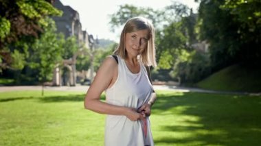 Yaşlı bir kadın parkta duruyor ve belini ölçüyor. O neticeye sevinir..