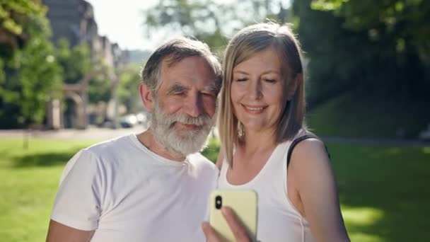 Ηλικιωμένοι άνδρες και γυναίκες στο πάρκο μετά την καλή φυσική κατάσταση τραβήξτε φωτογραφίες του εαυτού τους στο τηλέφωνο. — Αρχείο Βίντεο