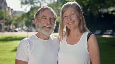 Spor salonundan sonra parkta yaşlı bir adam ve kadın eğleniyor. Gülümsüyorlar. Gri saçlı sakallı adam ve uzun saçlı kadın..