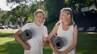 Parkta ellerinde spor minderleriyle yürüyen iki yaşlı insan. Güzel konuşuyorlar..