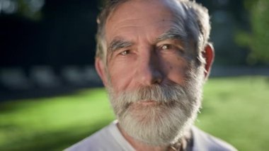 Sakallı, gri saçlı adamın yüzü. Şu anda parkta..