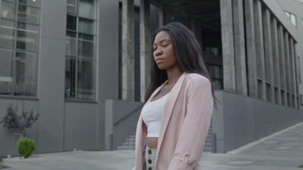 Hermosa joven negra se para en la calle. Bastante seria chica con el pelo largo. — Vídeos de Stock