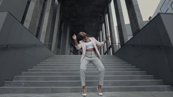 Junges schwarzes Mädchen tanzt Modern Dance auf der Treppe. Sie trägt Businesskleidung mit High Heels. Sie bewegt aktiv ihre Hände. — Stockvideo